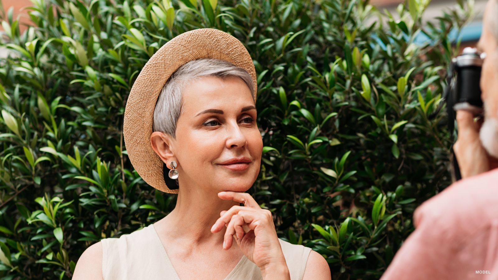 mature woman getting her photo taken. The photographer is to the right with a small part of the camera in frame