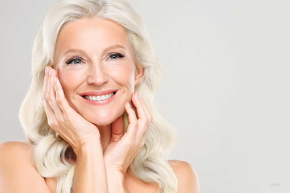 Mature woman with white hair touching her face