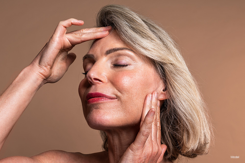 Mature woman with blonde hair touching her face